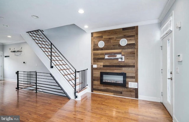 living room featuring a large fireplace, hardwood / wood-style flooring, and crown molding