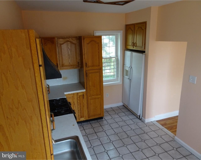 kitchen featuring black gas stove, extractor fan, white refrigerator with ice dispenser, and sink