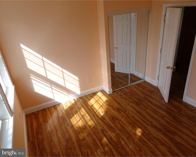 unfurnished bedroom featuring a towering ceiling, hardwood / wood-style flooring, and a closet