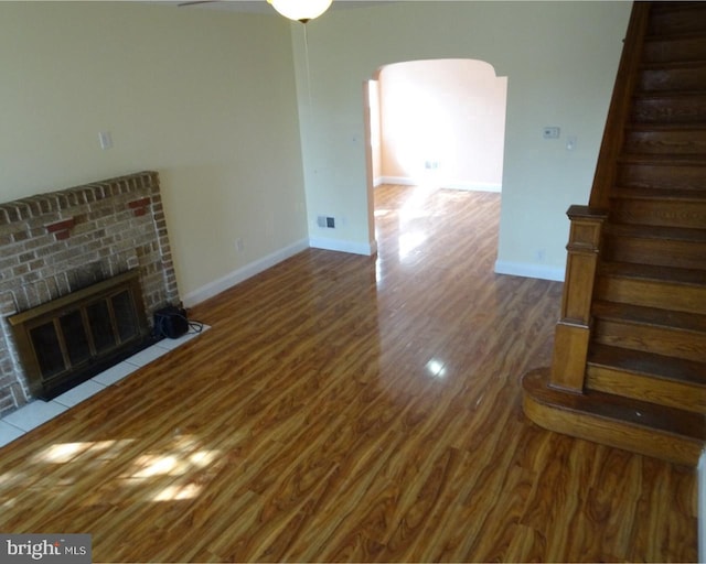 unfurnished living room featuring a brick fireplace, ceiling fan, and hardwood / wood-style flooring