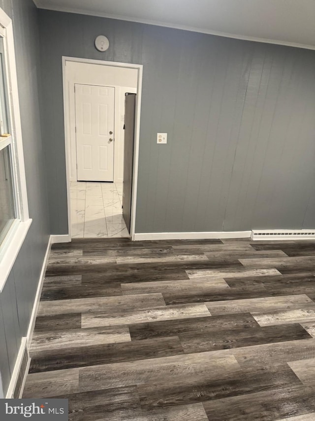 unfurnished room featuring ornamental molding, dark wood-type flooring, and wood walls