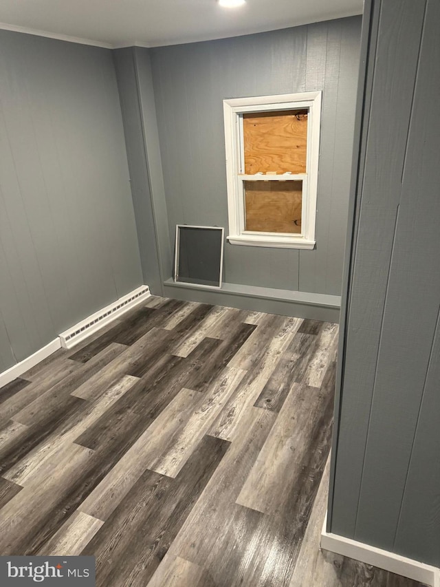 empty room with a baseboard radiator, dark hardwood / wood-style floors, and wood walls