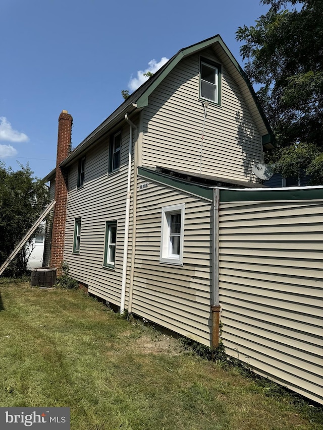 view of home's exterior featuring a lawn, a chimney, and central AC unit