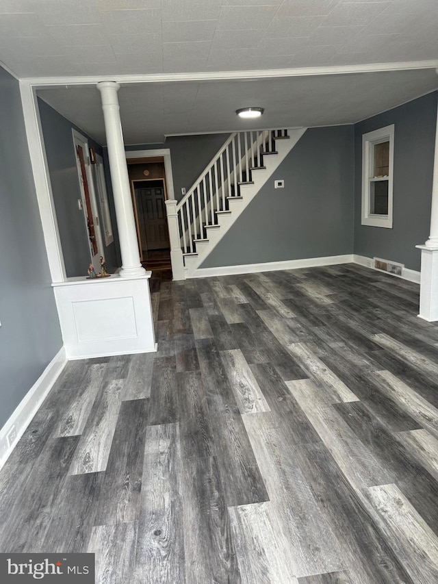 unfurnished living room featuring decorative columns and dark hardwood / wood-style flooring