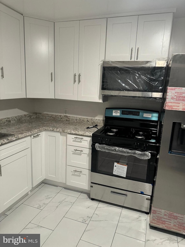 kitchen with stainless steel appliances, white cabinets, and light stone counters