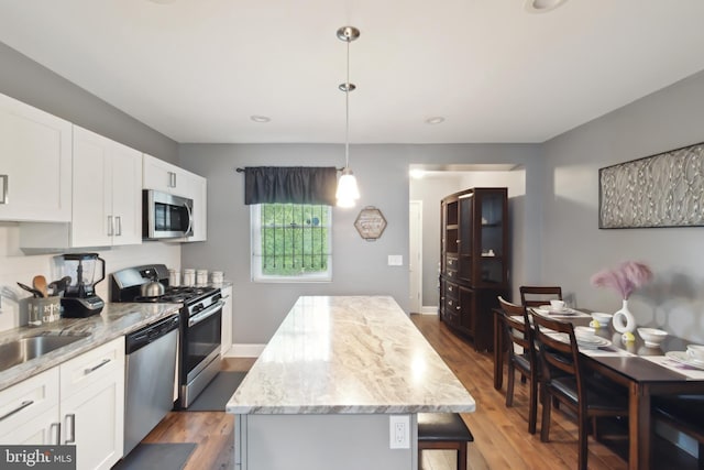 kitchen with appliances with stainless steel finishes, a center island, pendant lighting, and white cabinets