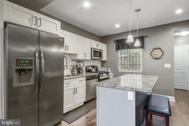 3220 Elmley Ave, Baltimore, MD 21213 - kitchen with pendant lighting, a kitchen island, white cabinets, and appliances with stainless steel finishes