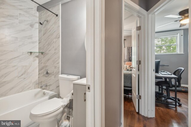 full bathroom featuring vanity, hardwood / wood-style flooring, ceiling fan, tiled shower / bath, and toilet