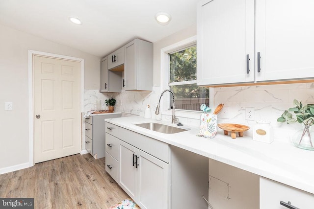 kitchen with vaulted ceiling, tasteful backsplash, light hardwood / wood-style flooring, and sink