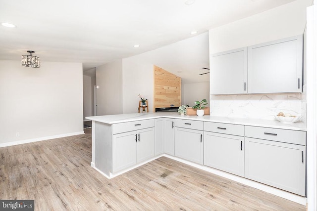 kitchen with pendant lighting, kitchen peninsula, decorative backsplash, light hardwood / wood-style floors, and white cabinetry