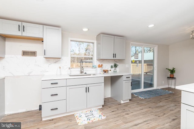 kitchen with decorative backsplash, sink, and light hardwood / wood-style floors