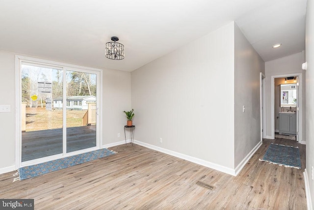 unfurnished dining area featuring a notable chandelier, vaulted ceiling, and light hardwood / wood-style flooring