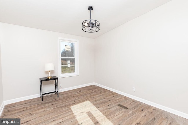 unfurnished room featuring a chandelier and light hardwood / wood-style flooring