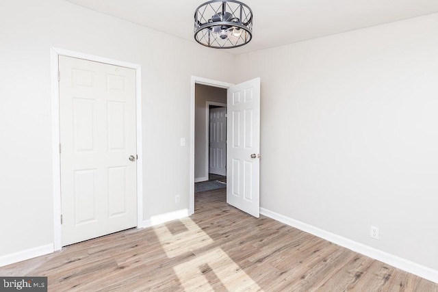 unfurnished bedroom featuring a notable chandelier and light hardwood / wood-style floors