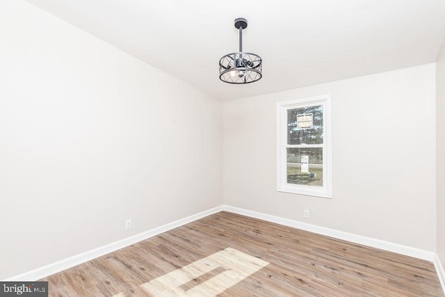 empty room featuring light wood-type flooring and an inviting chandelier