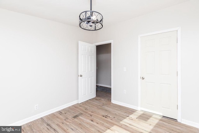 unfurnished bedroom featuring a notable chandelier and light hardwood / wood-style floors