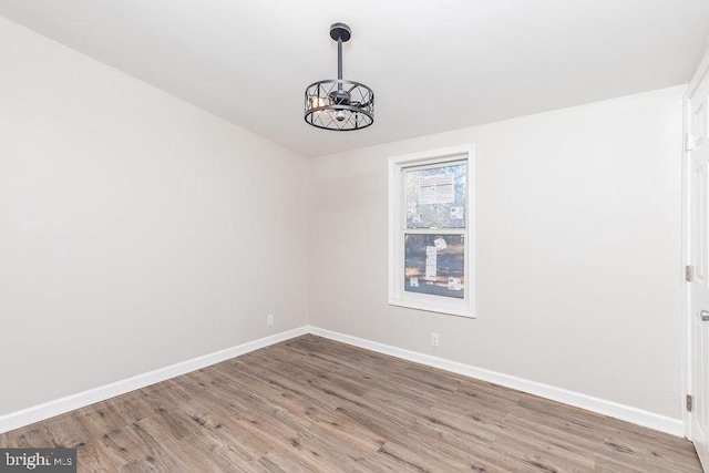 unfurnished room with hardwood / wood-style flooring and a notable chandelier