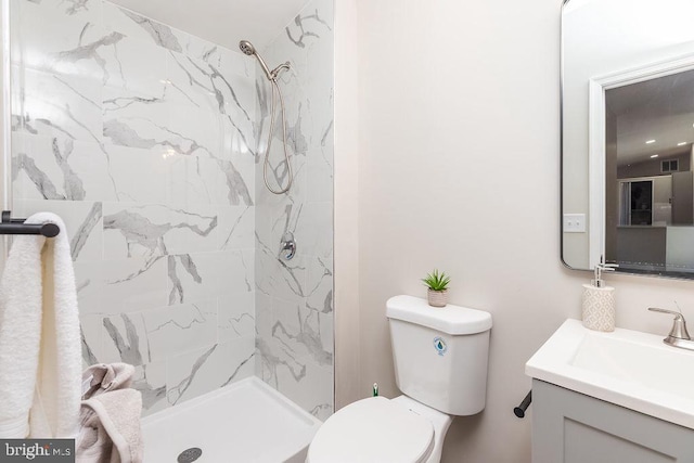 bathroom featuring a tile shower, vanity, and toilet