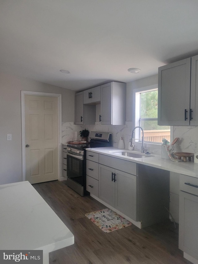 kitchen featuring lofted ceiling, backsplash, sink, dark hardwood / wood-style floors, and stainless steel range oven