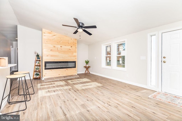 unfurnished living room featuring ceiling fan, a large fireplace, light hardwood / wood-style floors, and lofted ceiling