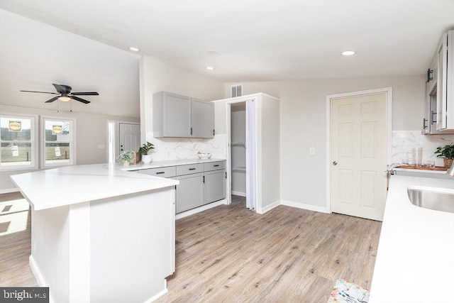 kitchen with kitchen peninsula, decorative backsplash, sink, and vaulted ceiling