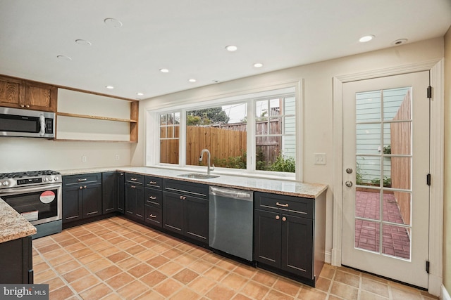 kitchen with light stone counters, stainless steel appliances, and sink