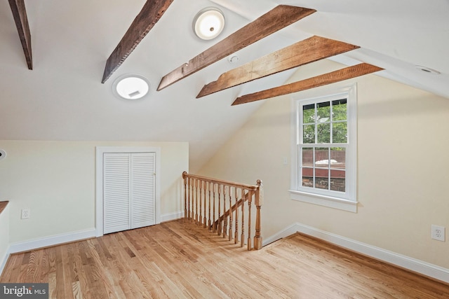 additional living space with lofted ceiling with beams and light wood-type flooring