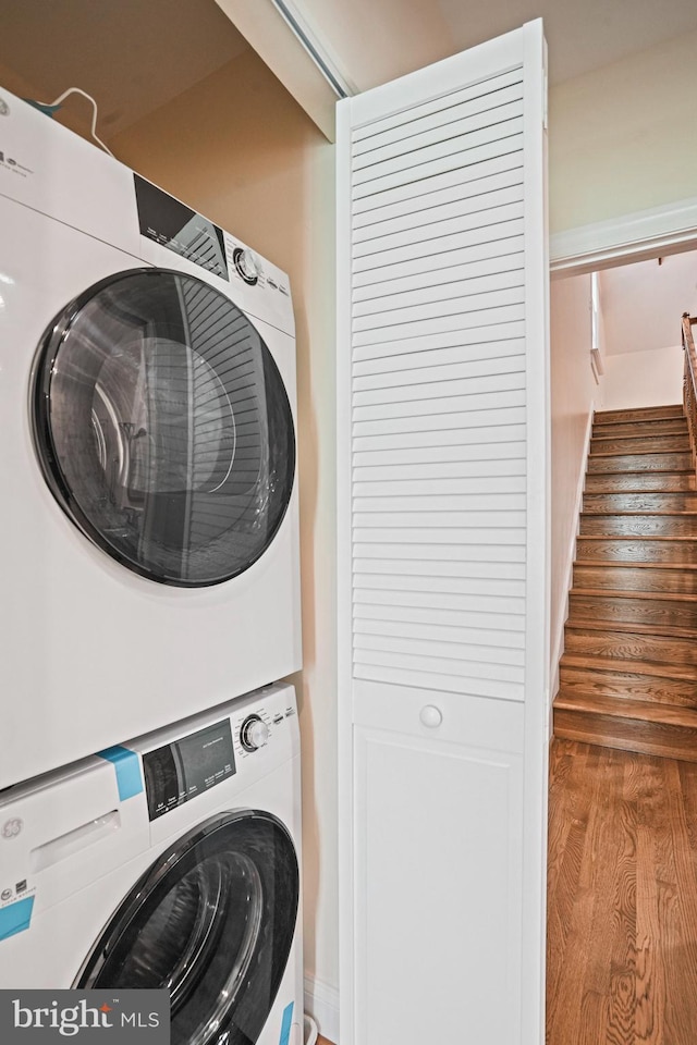 laundry room with stacked washer / drying machine and hardwood / wood-style floors