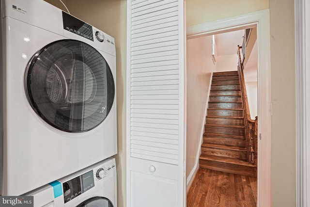 clothes washing area featuring dark wood-type flooring and stacked washing maching and dryer