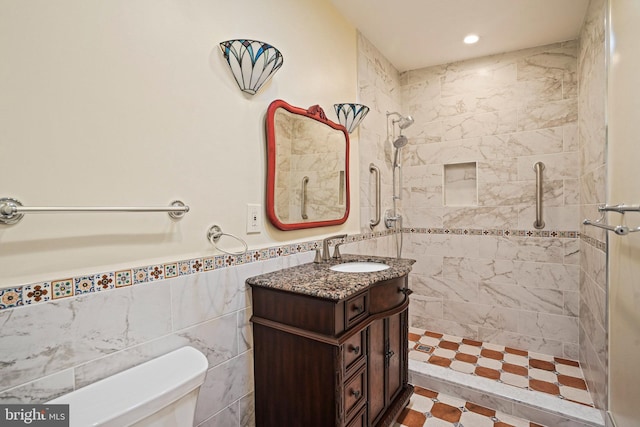 bathroom featuring tiled shower, vanity, toilet, and tile walls