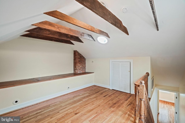 bonus room with lofted ceiling with beams and light wood-type flooring