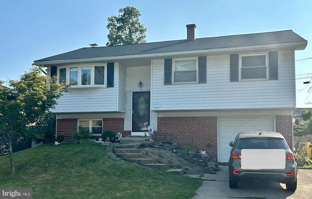 raised ranch featuring a front lawn, brick siding, a garage, and concrete driveway