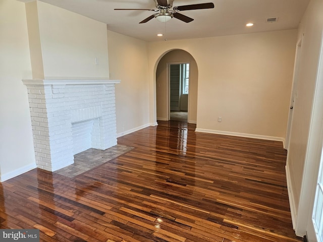 unfurnished living room with ceiling fan, a fireplace, and dark hardwood / wood-style flooring