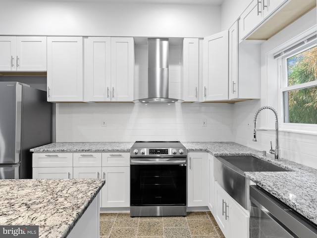 kitchen with appliances with stainless steel finishes, wall chimney exhaust hood, white cabinetry, and sink