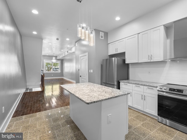 kitchen with a kitchen island, hardwood / wood-style floors, stainless steel appliances, white cabinetry, and wall chimney range hood