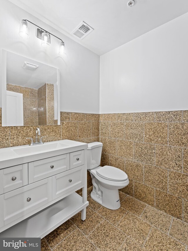 bathroom with vanity, tile walls, and toilet