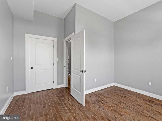 spare room with baseboards and wood finished floors