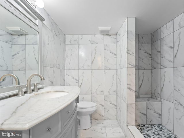 bathroom with tile walls, toilet, tiled shower, and vanity