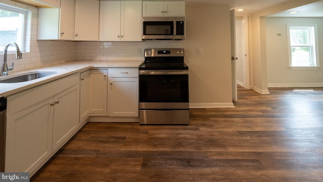 kitchen featuring sink, stainless steel appliances, white cabinetry, and dark wood-type flooring