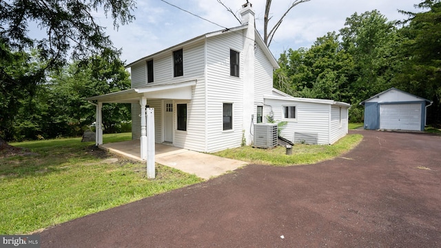 view of front of house featuring cooling unit, an outbuilding, a garage, and a front lawn