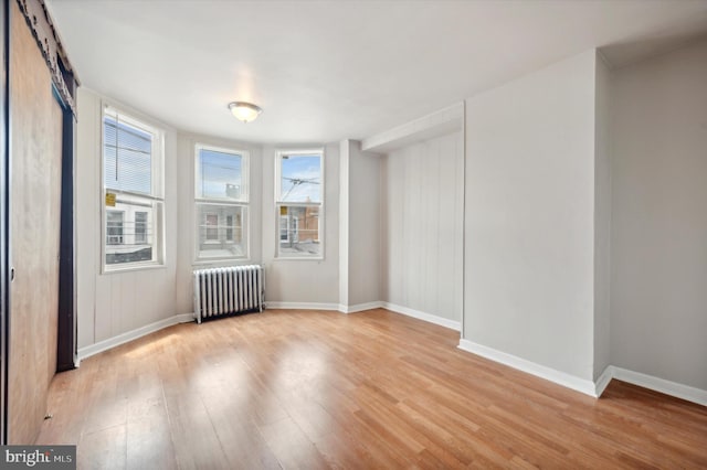 empty room with light hardwood / wood-style floors and radiator