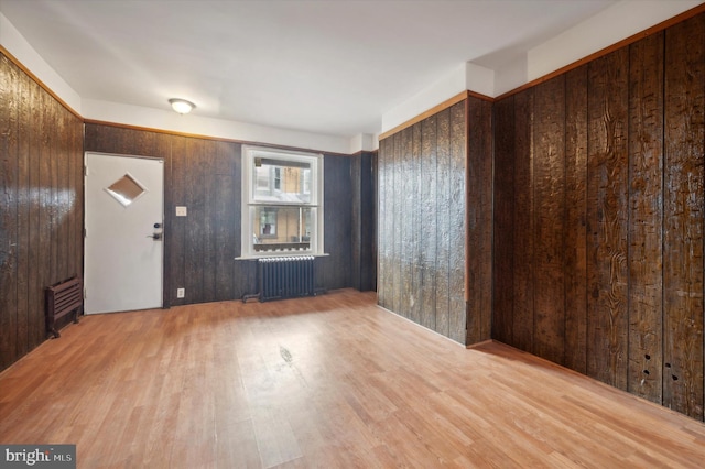 foyer featuring wood walls, radiator, and wood-type flooring