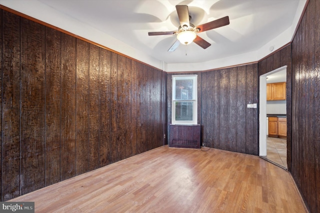 empty room with wooden walls, light tile patterned floors, and ceiling fan