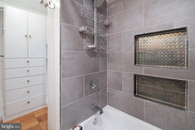 bathroom featuring parquet floors and tiled shower / bath