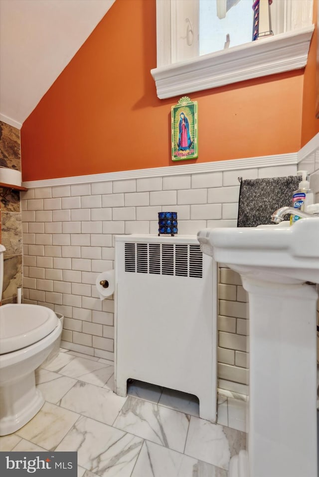 bathroom featuring toilet, tile walls, radiator, and vaulted ceiling