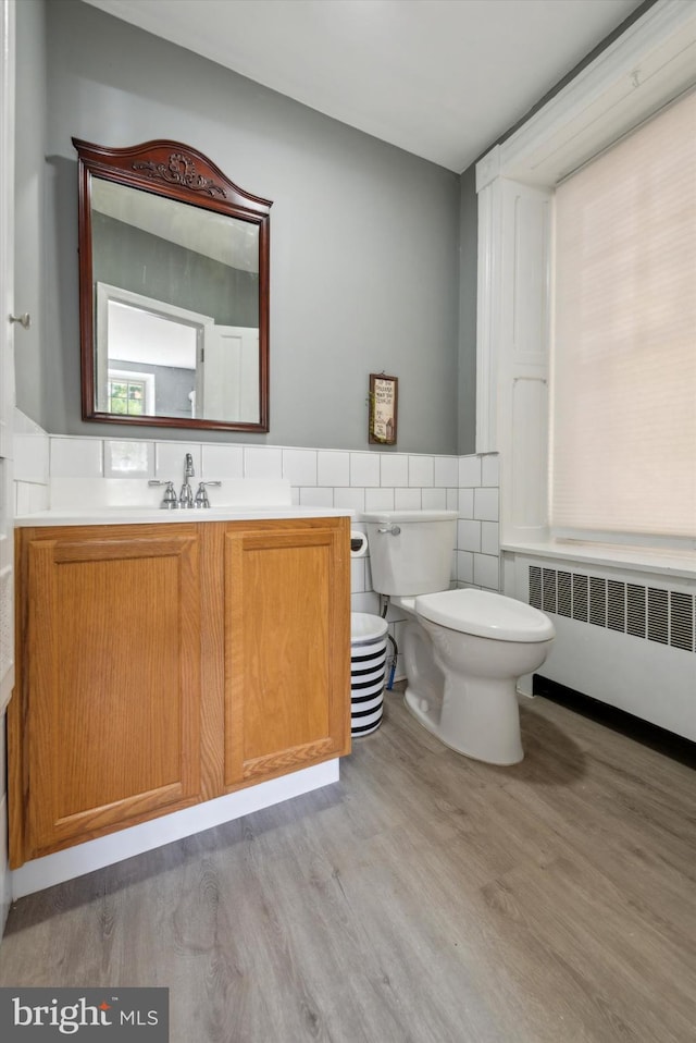 bathroom featuring hardwood / wood-style flooring, vanity, toilet, and radiator