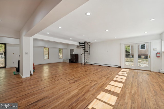 unfurnished living room with light wood-type flooring and a baseboard heating unit