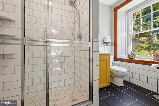 bathroom featuring tile patterned flooring, toilet, tile walls, and walk in shower