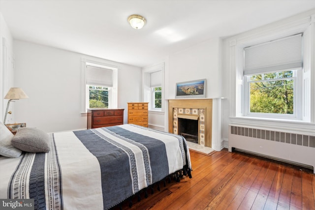 bedroom featuring radiator heating unit, dark hardwood / wood-style flooring, and multiple windows