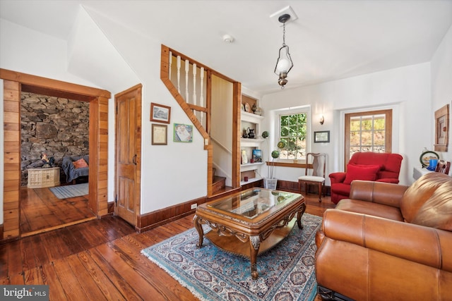 living room featuring a stone fireplace and dark wood-type flooring